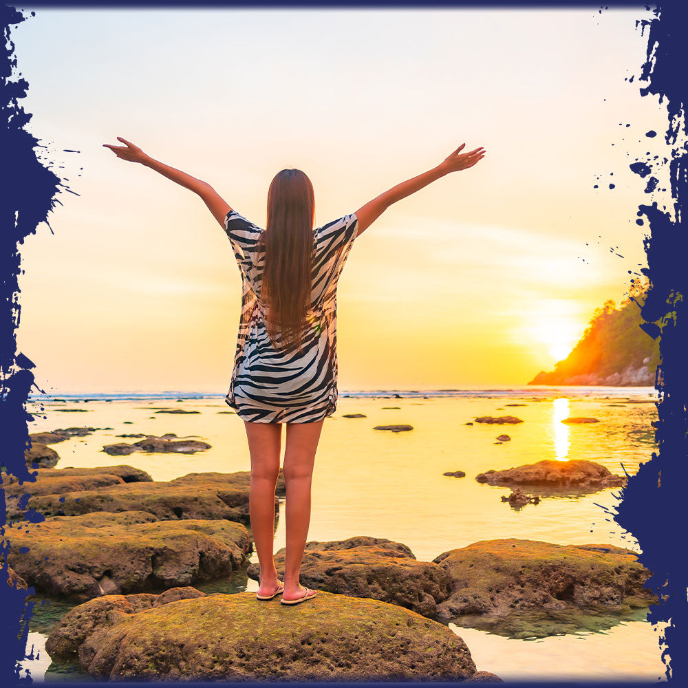 Person with arms outstretched on a beach at sunset, representing Pro-Fit's travel rewards.